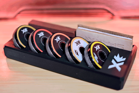 Sparx Grinding Ring Organizer holding five colorful grinding rings on a sleek black tray with a leather honing strip in the background, designed for efficient and organized skate sharpening.